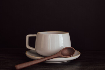 Coffee cup on saucer with wood spoon on a black background