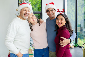 Diverse couples wearing cozy sweaters and Santa hats celebrating in living room with Christmas tree