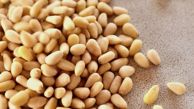 Peeled pine nuts. Close-up of pine nut kernels fall on a ceramic plate.Healthy fats in nutrition