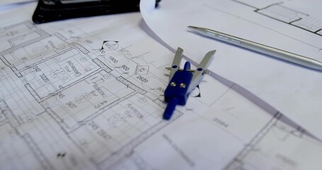 Featuring drafting compass resting on blueprints at studio desk, with silver pen and tablet © vectorfusionart
