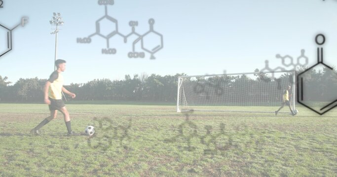 Dribbling player in yellow jersey on grass field with goal net, chemical diagrams, copy space