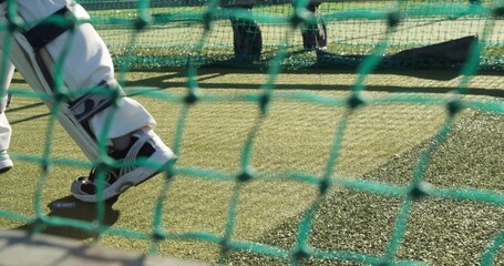 Moving batsman lower legs wearing batting pads and white pants training in practice net, copy space