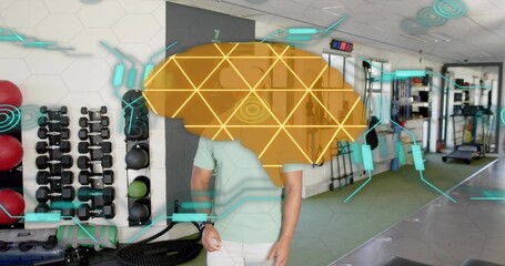 Standing male wearing mint green polo viewing holographic brain overlay in gym, with dumbbell rack