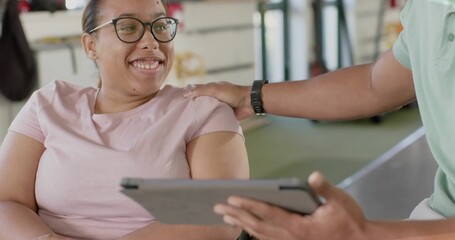 Smiling woman sitting in pink tee, trainer in green polo holding tablet at gym, copy space