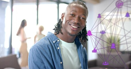 Smiling man with braids wearing denim shirt in lounge, team talking by windows, purple overlay