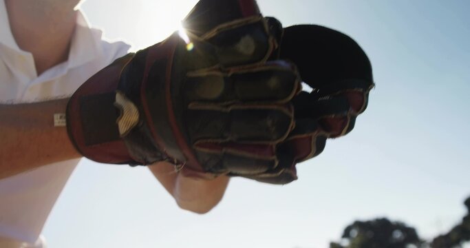 Naklejki Holding padded glove toward camera on sports field, showing white polo sleeve and sun halo