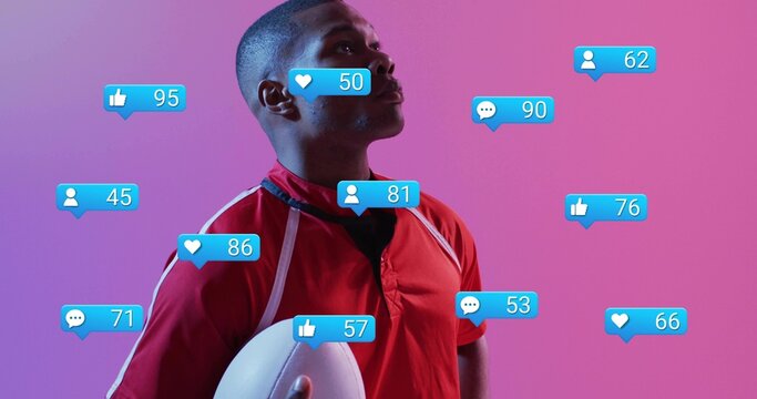 Holding white football, red jersey athlete with black tee posing in pink studio with blue icons - Powered by Adobe