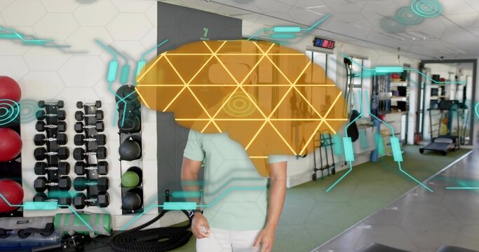 Standing male wearing mint green polo viewing holographic brain overlay in gym, with dumbbell rack
