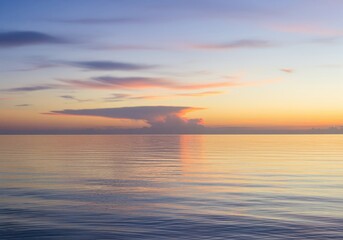 Obraz premium Breathtaking tranquil dawn over a calm sea with soft wispy pastel clouds