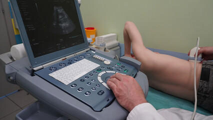 Ultrasound examination of a patient in a supine position. The doctor controls the ultrasound machine and performs kidney diagnostics, the data is displayed on the monitor in real time.