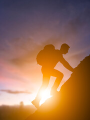 Man climbing mountain at sunrise silhouette