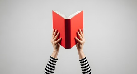 Hands holding open a bright red book against a plain background