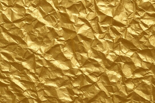 Luxurious crumpled gold foil texture with soft highlights and deep metallic shadows - Powered by Adobe