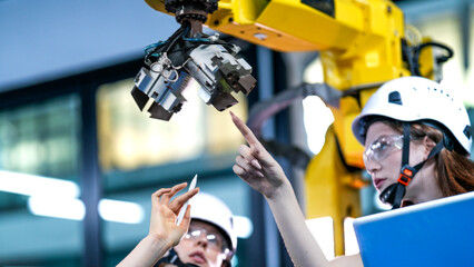 Two female robotics engineers in an R and D lab program an artificial intelligence system. They are...