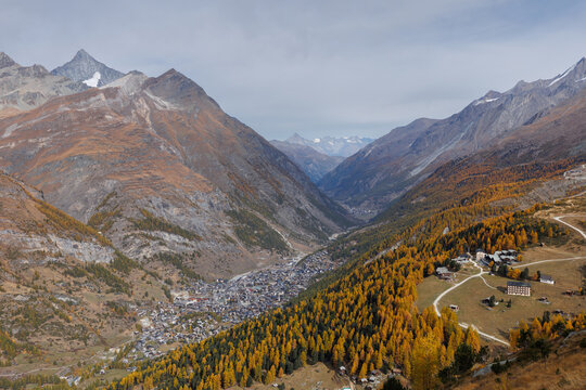 View down the Matter valley with Zermatt below in autumn with trees turning orange, Switzerland