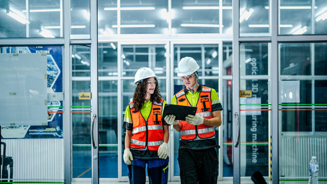 A diverse engineering team plans the future of work using a tablet. They are developing high-tech AI robotics and chip solutions for advanced manufacturing.