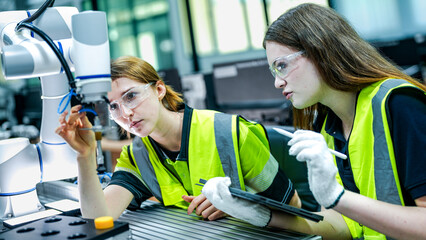 Two female engineers represent the future of work, using AI and robotics to optimize production....