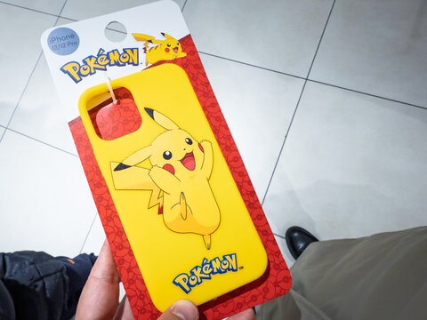 BELGRADE, SERBIA - OCTOBER 11, 2025: A hand holds a bright yellow phone case with the Pokemon logo and a cheerful Pikachu illustration inside a store in Belgrade, Serbia, a symbol of pokemon merch.