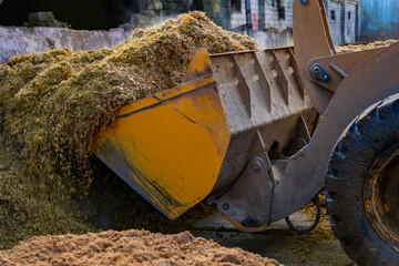 The front loader loads the feed into the feed dispenser on the farm