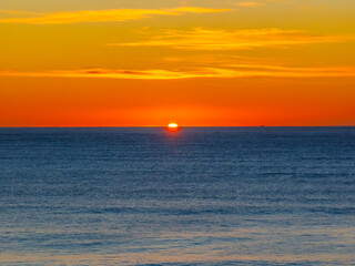 Ocean Sunrise Under Clear Skies with Orange Horizon
