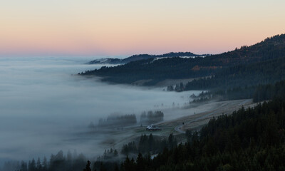 Early and cold autumn morning on Gurnigel viewing down on Gantrisch hut in the mist, Switzerland