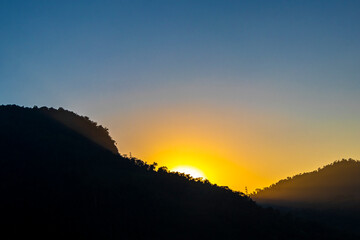 Golden colorful sunrise behind the tropical mountain mountains in Brazil.