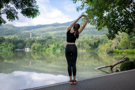 Woman stretching outdoors by lake for wellness