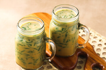 Cendol, a traditional Indonesian dessert drink. It is served in a clear glass mason jar. Captured with natural light.