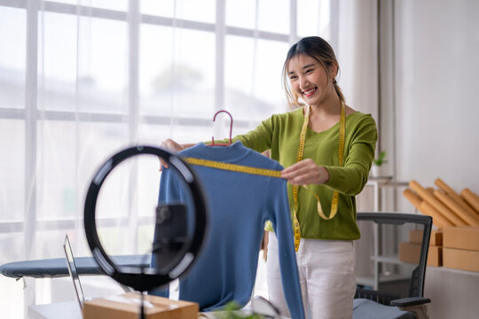 Fashion designer showing clothes measurements during live video call selling online via social media