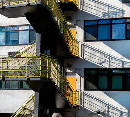 White Building with a Black and Green Fire Escape in Sunlight with Silhouettes.