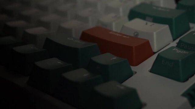 Keyboard with green, white, and orange keycaps under alternating bright and dark lighting, dramatic visual of digital workspace atmosphere.