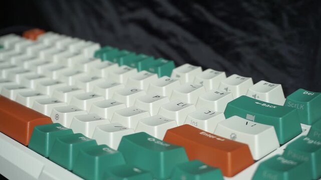 Keyboard with green, white, and orange keycaps under alternating bright and dark lighting, dramatic visual of digital workspace atmosphere.