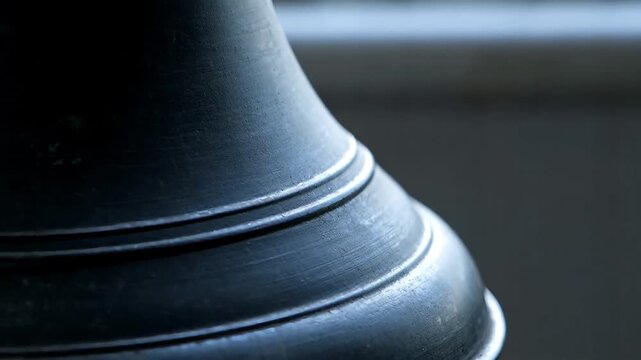 Extreme close-up macro shot of the curved, textured surface of a dark bronze or cast iron old historical bell against a black background