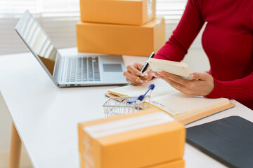 Small business owners working with laptops at home for ecommerce, SME startups, entrepreneurs working with receipt boxes and checking online orders.