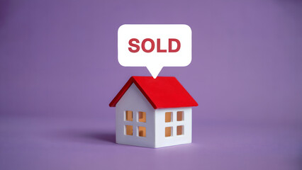A miniature house with a red roof and a speech bubble that says sold on a purple background space