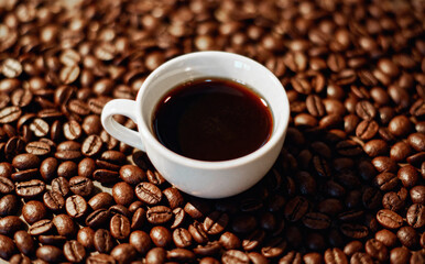 Cup of Black Coffee on Roasted Coffee Beans Background