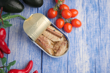 Sardines in tin with vegetables on a wooden table