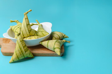 Traditional Malaysian ketupat palas neatly wrapped in palm leaves, placed on a wooden chopping...