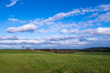 A gentle stretch of green hills under a blue sky with clouds