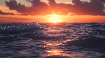 A vibrant sunset casts an orange glow on the waves of the ocean as the sun begins to set.