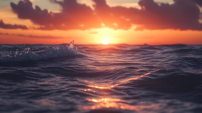 A vibrant sunset casts an orange glow on the waves of the ocean as the sun begins to set.
