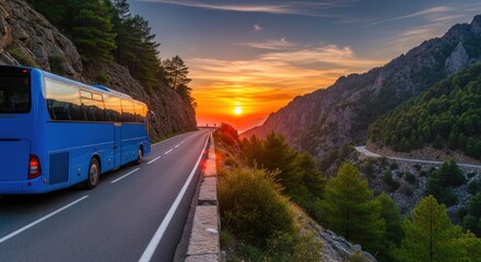 A blue bus driving down a winding mountain road at sunset.