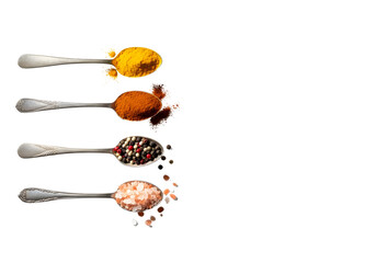 Four spoons of colorful spices turmeric, paprika, peppercorns, and pink salt on white