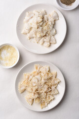 Farfalle pasta with white cream cheese sauce and black pepper, Italian food on a white plate