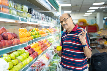 Senior indian man purchasing fruit at fruit shop. Healthy lifestyle concept.