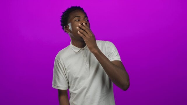 Young african american man hand over mouth yawning in studio; sleepiness exhaustion drowsiness fatigue.