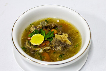 Special Oxtail Soup Sop Buntut in a white bowl Indonesian Food with Spices, Carrot, Lime, Corriander