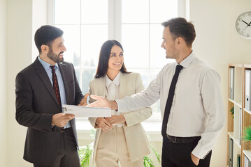 Smiling business people talk, happy closing successful deal, standing in office, satisfied hr...