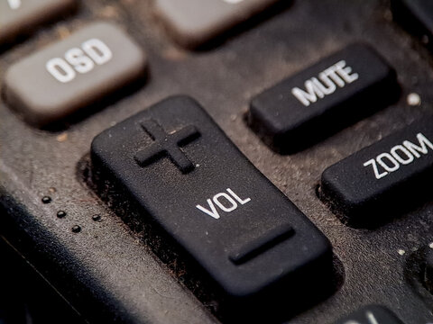 Close up view of a remote control panel showing volume mute and zoom functions clearly visible.