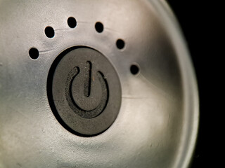Power button signifies activation with dot array on textured surface contrasting with dark backdrop.